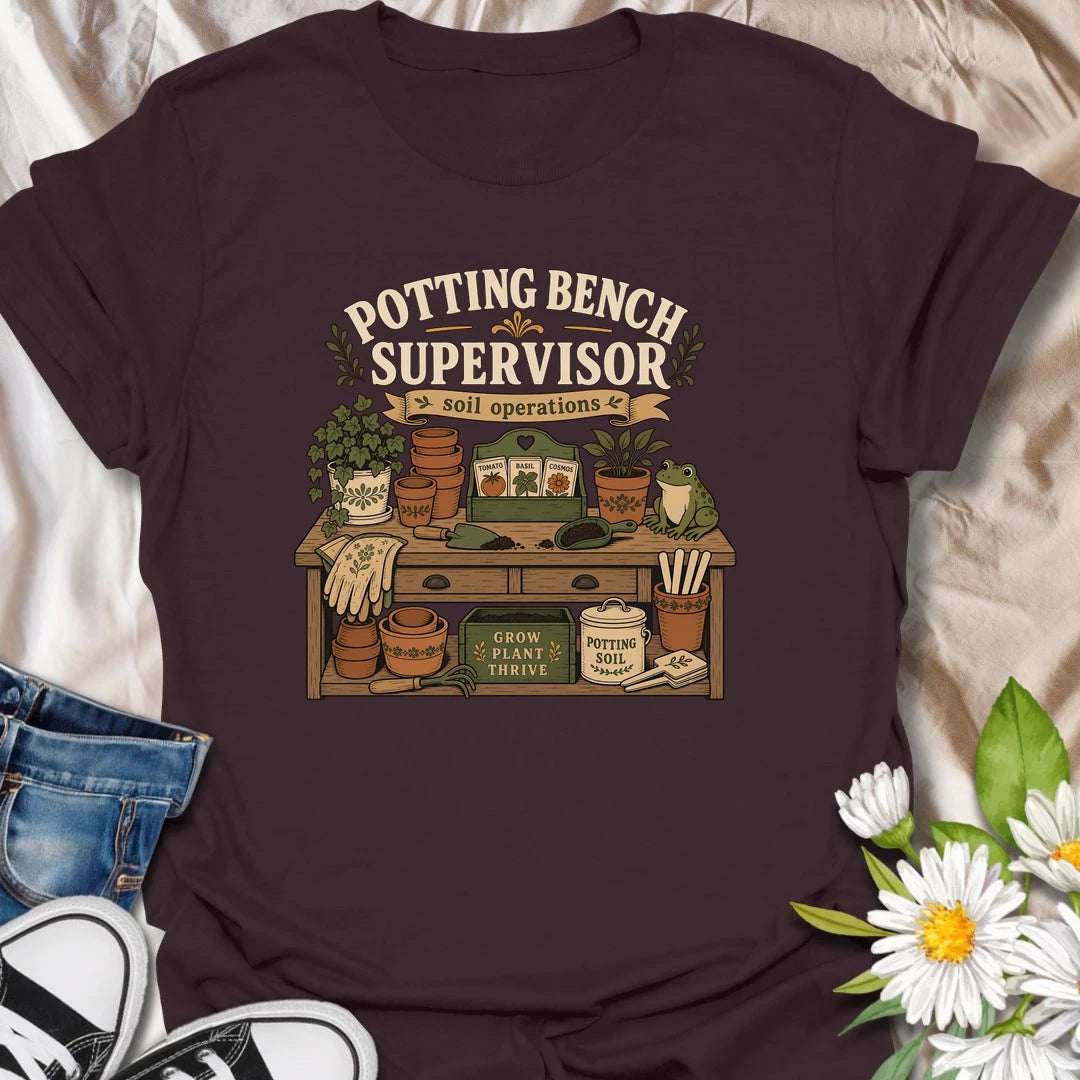 A vintage gardening T-shirt for anyone who considers the potting bench their personal headquarters. The detailed design features seed packets, terracotta pots, soil scoops, garden gloves, and a watchful frog supervisor. A fun gift for gardeners, seed starters, potting enthusiasts, and backyard growers.