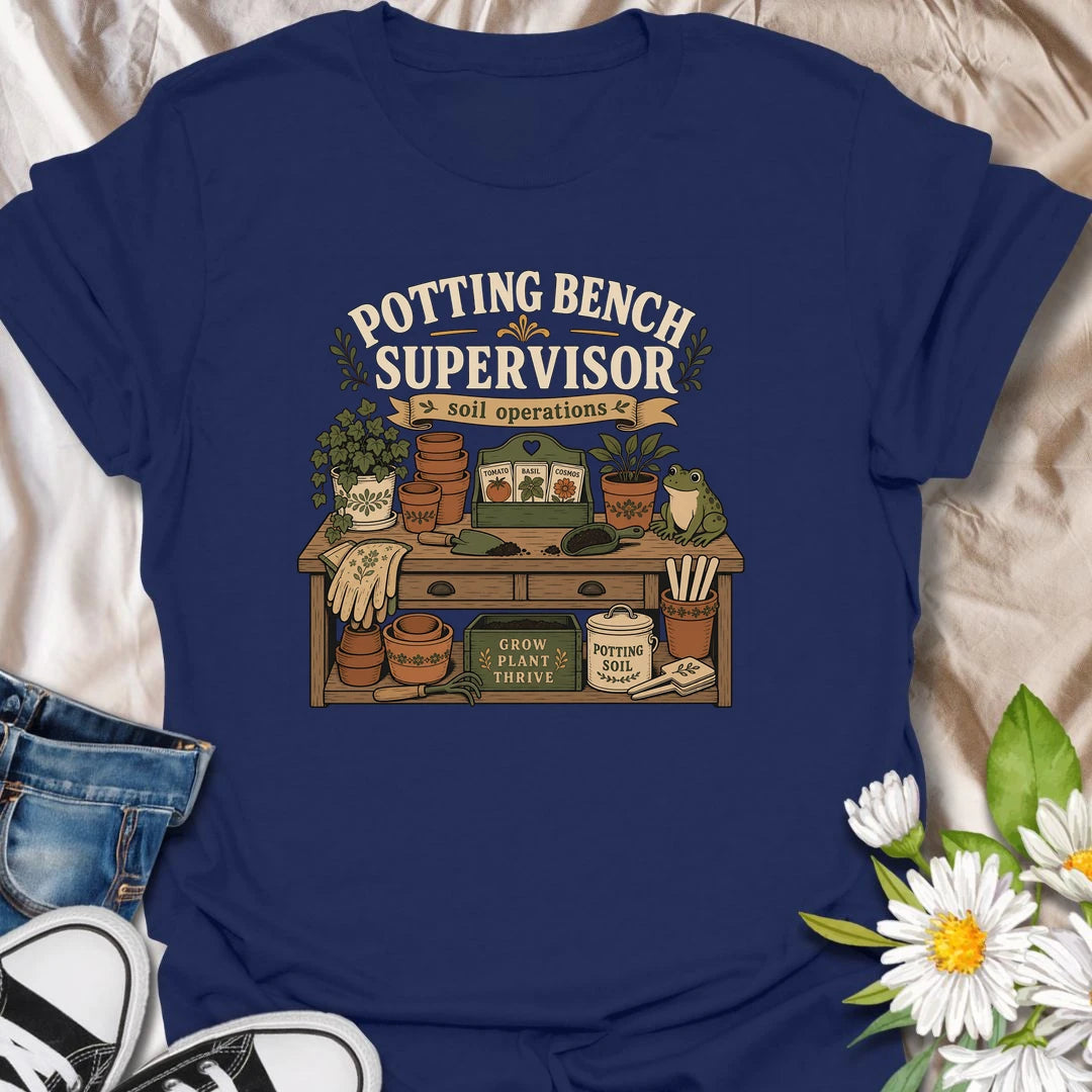 A vintage gardening T-shirt for anyone who considers the potting bench their personal headquarters. The detailed design features seed packets, terracotta pots, soil scoops, garden gloves, and a watchful frog supervisor. A fun gift for gardeners, seed starters, potting enthusiasts, and backyard growers.