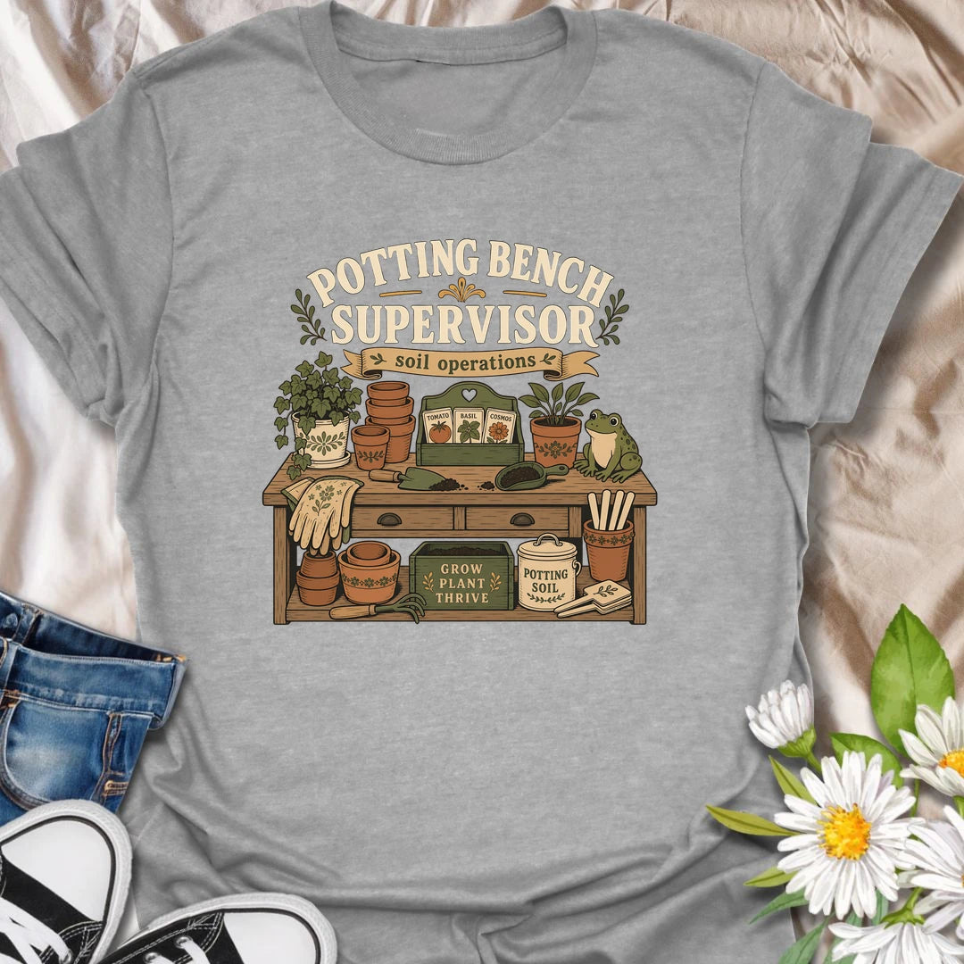 A vintage gardening T-shirt for anyone who considers the potting bench their personal headquarters. The detailed design features seed packets, terracotta pots, soil scoops, garden gloves, and a watchful frog supervisor. A fun gift for gardeners, seed starters, potting enthusiasts, and backyard growers.