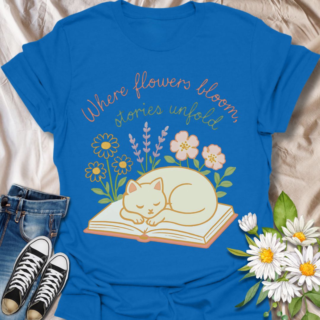 Cozy cat and book t-shirt with pastel flowers and the quote 'Where flowers bloom, stories unfold.' Perfect for book lovers, cat moms, gardeners, and daydreamers who adore cottagecore and literary aesthetics. Soft and sweet tee ideal for spring, reading nooks, and gifting.
