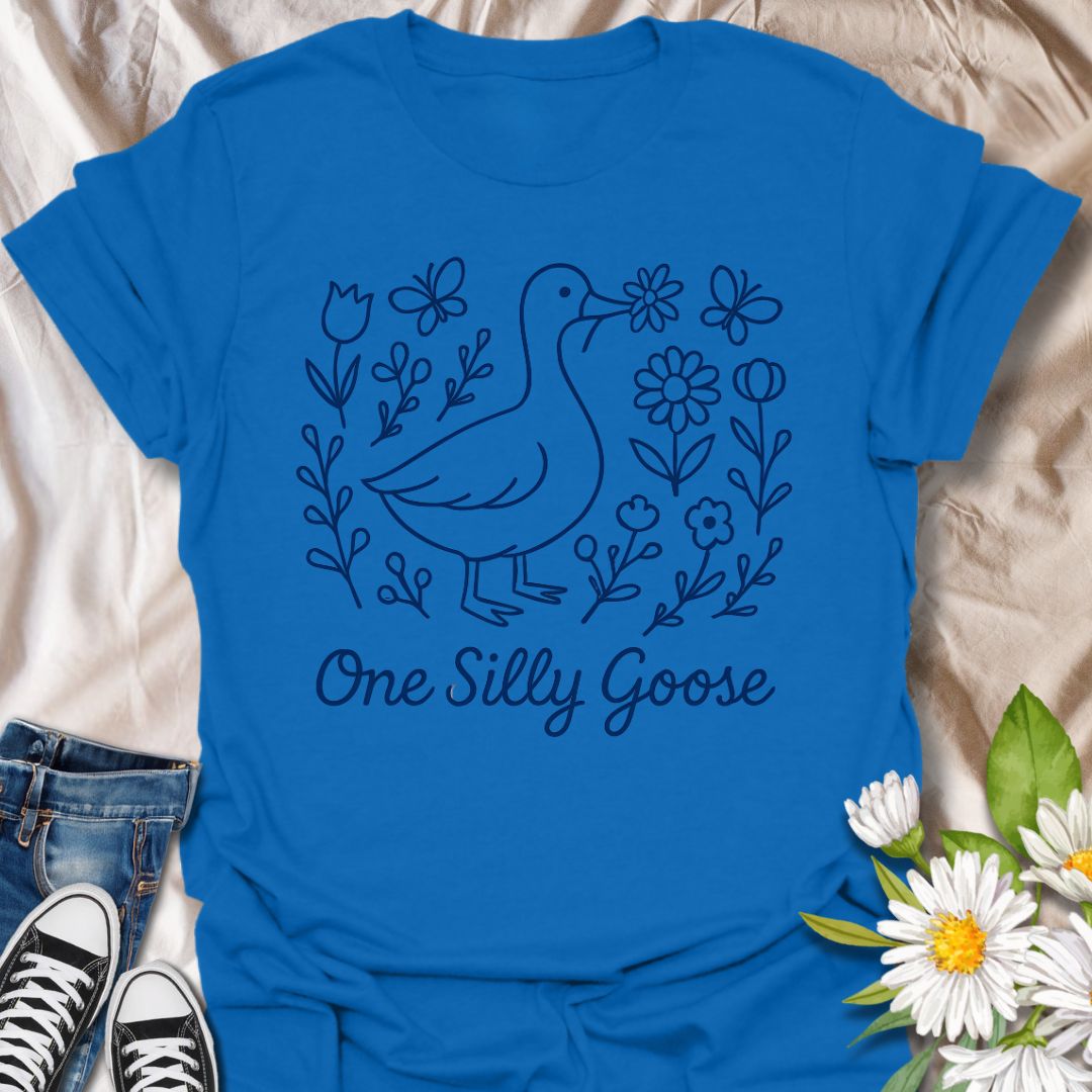 Adorable ‘One Silly Goose’ shirt with a playful goose surrounded by flowers and butterflies. Perfect for humor lovers, goose enthusiasts, and whimsical nature apparel fans.