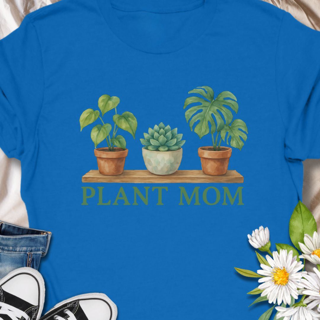 Show off your green thumb with this charming “Plant Mom” t-shirt featuring potted plants on a wooden shelf. Ideal for plant lovers, indoor gardeners, or anyone who adores succulents and tropical houseplants. This tee makes a perfect gift for Mother's Day, birthdays, or just to treat yourself with botanical flair.