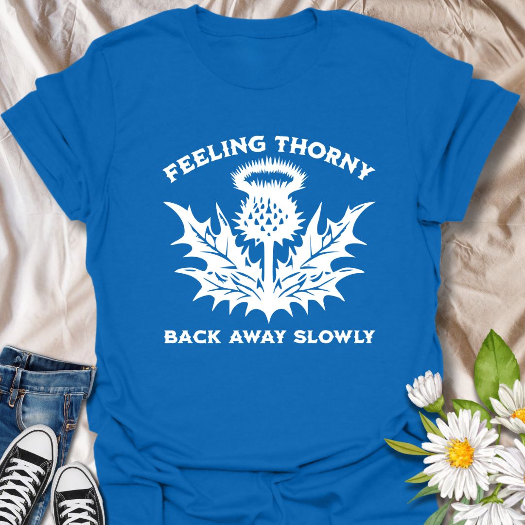 Embrace your mood with this witty “Feeling Thorny – Back Away Slowly” t-shirt featuring a bold thistle graphic. Perfect for introverts, plant lovers, and anyone with a sharp sense of humor, this quirky design makes a great gift or statement piece for everyday wear.
