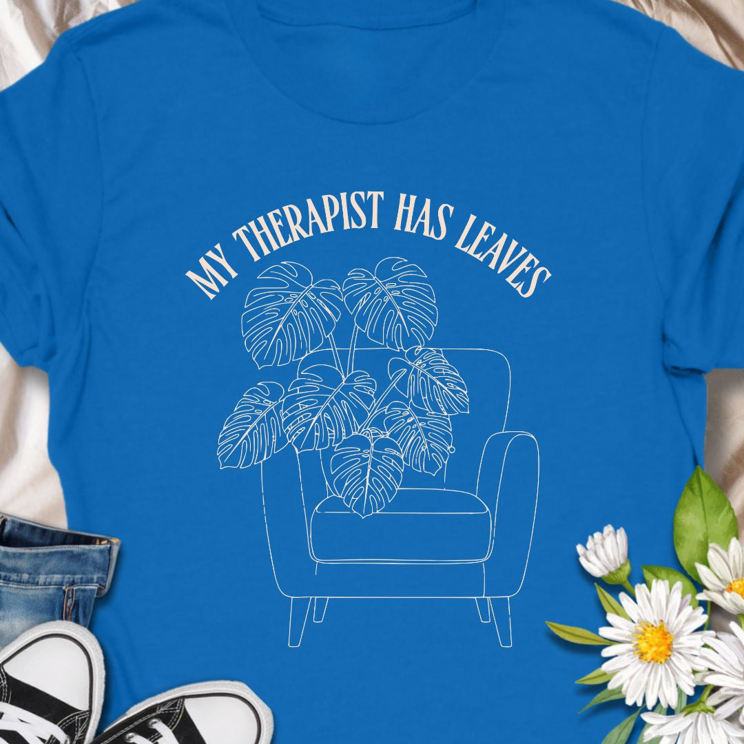 For plant people who spill their heart out to their houseplants, this “My Therapist Has Leaves” t-shirt says it all. Features a cozy armchair and lush monstera, making it the perfect aesthetic plant lover tee for self-care days.