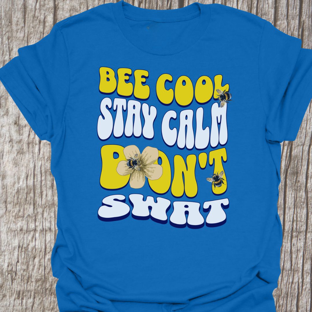 "Bee Cool, Stay Calm, Don't Swat" shaped text in white and yellow with images of bees and flowers.  Royal blue colored T-shirt