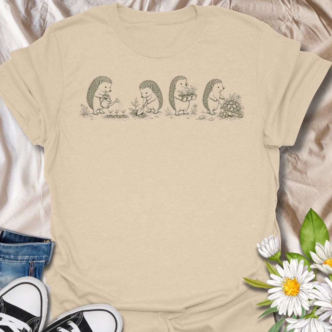 This Gardening Hedgehogs t-shirt is made for gardeners, nature lovers, and woodland animal fans who enjoy sweet vintage-style artwork. Featuring four charming hedgehogs watering, digging, carrying plants, and pushing a flower-filled wheelbarrow, this design has a gentle cottagecore garden feel. Perfect for plant lovers, gardeners, hedgehog fans, wildlife lovers, botanical art fans, and anyone who loves soft nature-inspired designs.