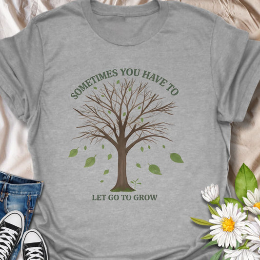 Embrace change and personal growth with this inspirational “Sometimes You Have to Let Go to Grow” t-shirt. Featuring a minimalist tree shedding leaves, this motivational nature-themed design is perfect for anyone navigating transformation, healing, or new beginnings. A thoughtful gift for plant lovers, nature fans, or those on a journey of self-growth.