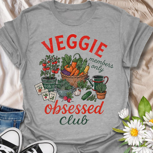This Veggie Obsessed Club t-shirt is perfect for gardeners, vegetable lovers, and homegrown food fans. Featuring a colorful illustrated harvest scene with tomatoes, carrots, cucumbers, seed packets, and a watering can, this fun gardening tee is great for anyone who loves growing their own food and spending time in the garden.