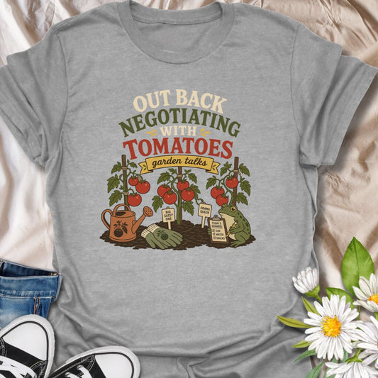 A funny vegetable gardening T-shirt for anyone who spends time discussing terms with their tomato plants. The design features ripe tomatoes, garden tools, plant stakes, and a frog recording the plants’ demands. A playful gift for tomato growers, backyard gardeners, and vegetable garden enthusiasts