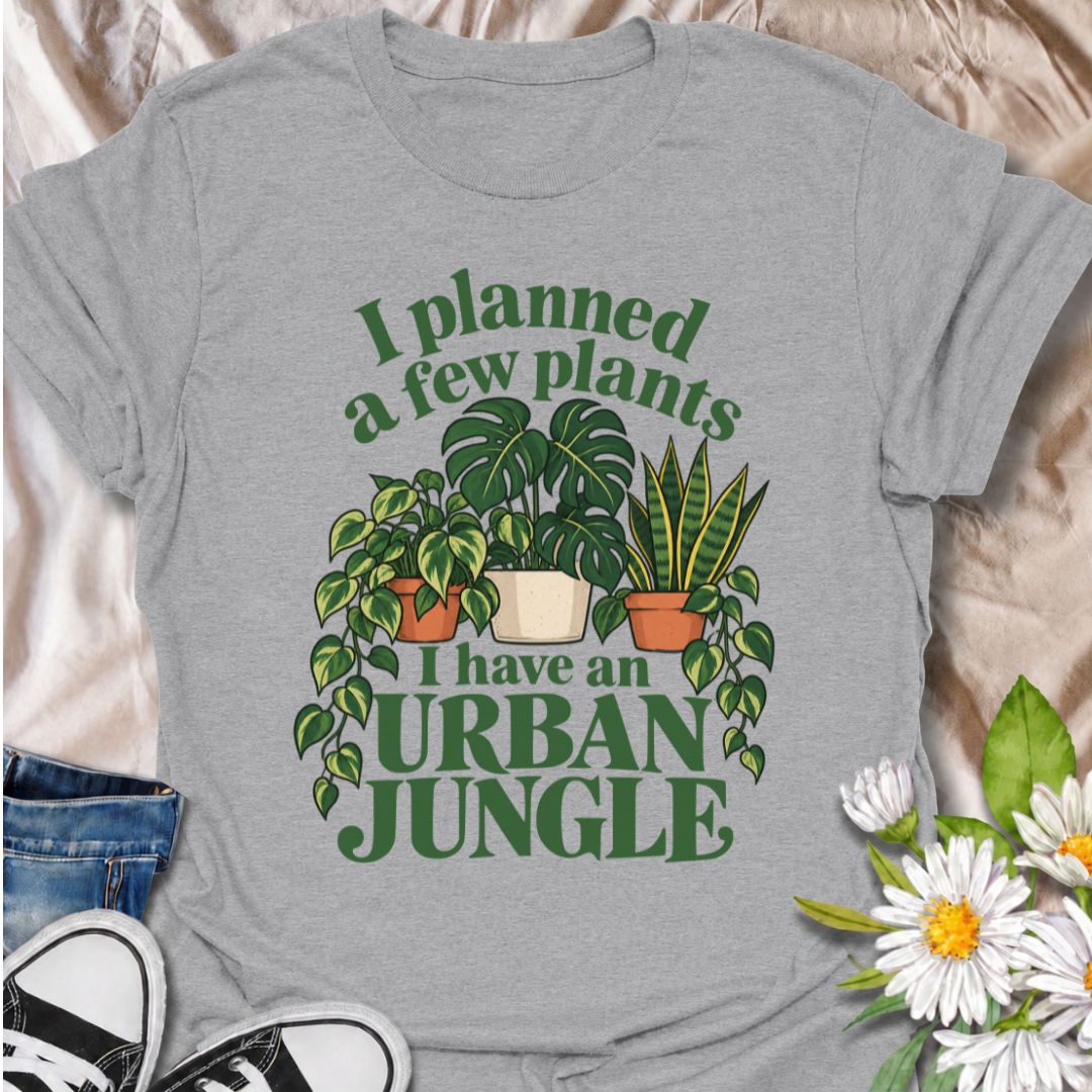 A funny plant T-shirt for anyone who started with a few houseplants and somehow ended up living in an indoor jungle. The phrase “I Planned a Few Plants. I Have an Urban Jungle.” captures the familiar reality of plant collecting with light, relatable humor. Featuring monstera, pothos, and snake plants, this design is perfect for plant parents, houseplant collectors, and indoor gardeners. It makes a great gift for anyone whose shelves, windowsills, and corners have slowly disappeared behind greenery. Perfect 