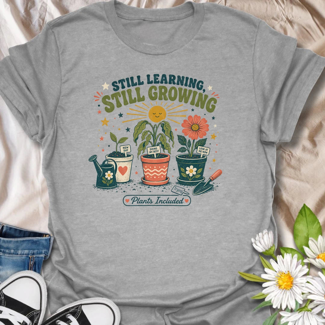 Encouraging plant t-shirt with cheerful garden pots, flowers, and a soft growth message for plant lovers and gardeners.