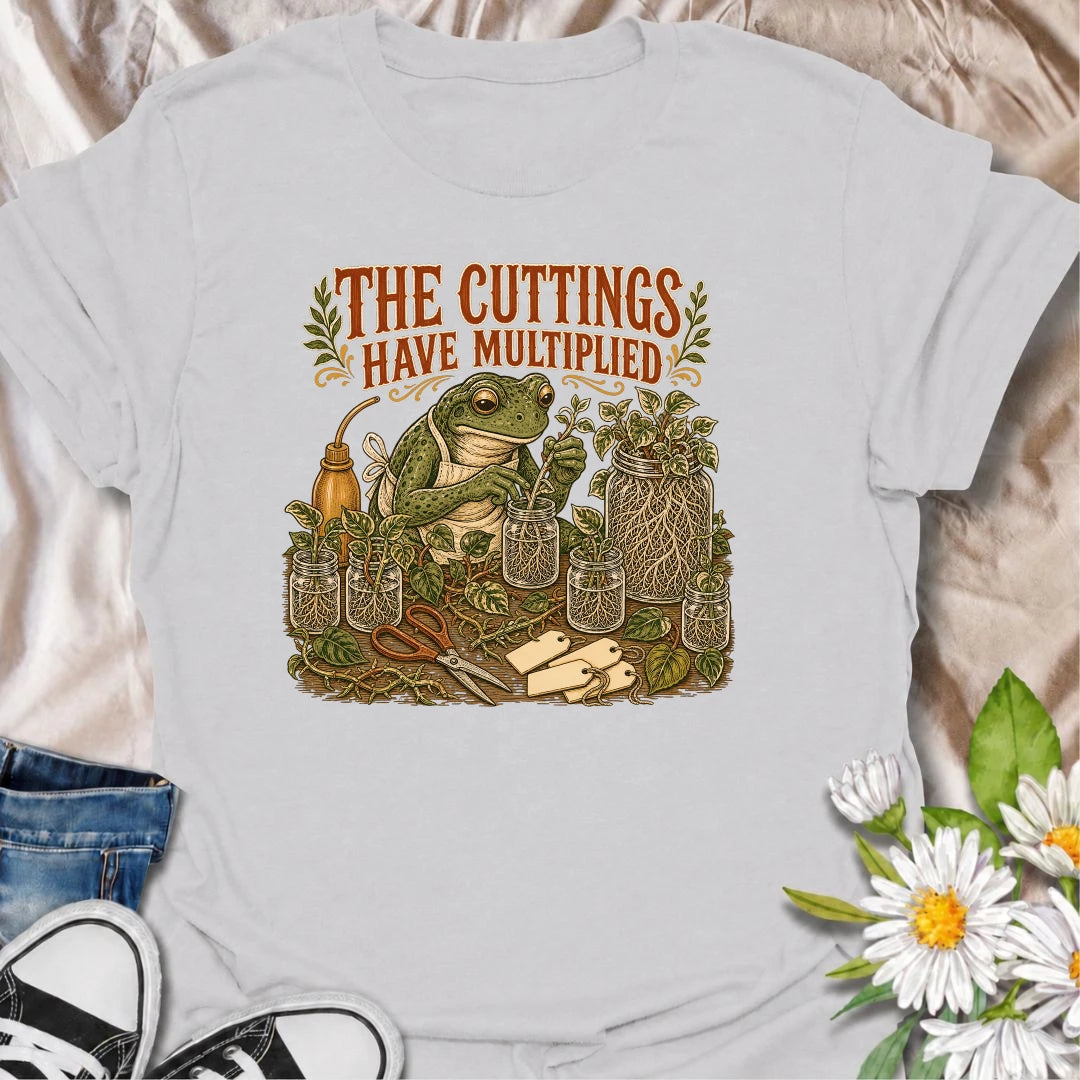 Celebrate a propagation collection that keeps growing with this funny “The Cuttings Have Multiplied” T-shirt. Featuring a charming frog surrounded by rooted plant cuttings, glass jars, scissors, and trailing vines, it is perfect for enthusiastic houseplant propagators. A playful gift for plant moms, pothos lovers, and anyone whose plant babies have taken over.