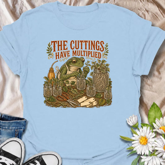 Celebrate a propagation collection that keeps growing with this funny “The Cuttings Have Multiplied” T-shirt. Featuring a charming frog surrounded by rooted plant cuttings, glass jars, scissors, and trailing vines, it is perfect for enthusiastic houseplant propagators. A playful gift for plant moms, pothos lovers, and anyone whose plant babies have taken over.