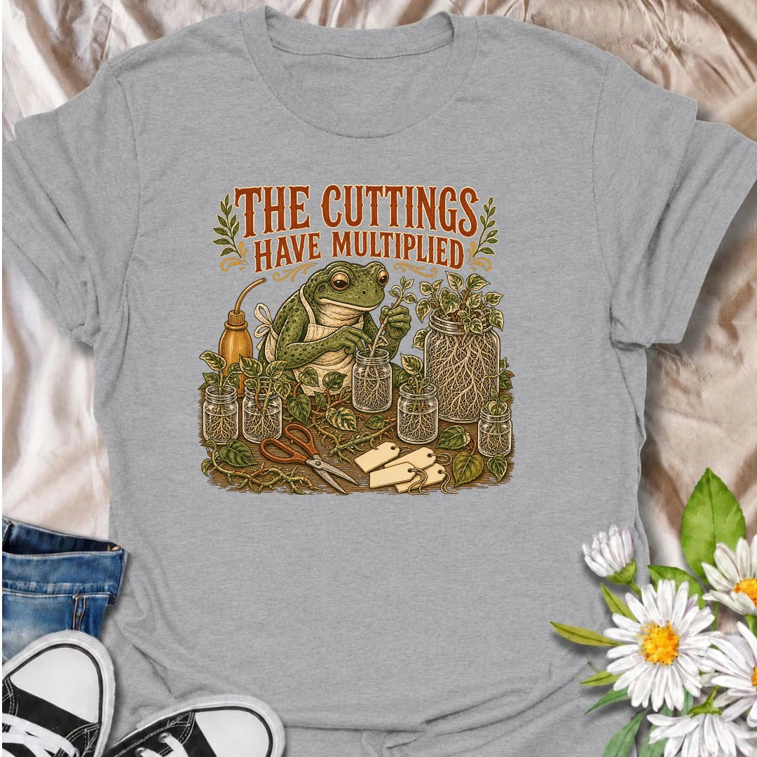 Celebrate a propagation collection that keeps growing with this funny “The Cuttings Have Multiplied” T-shirt. Featuring a charming frog surrounded by rooted plant cuttings, glass jars, scissors, and trailing vines, it is perfect for enthusiastic houseplant propagators. A playful gift for plant moms, pothos lovers, and anyone whose plant babies have taken over.