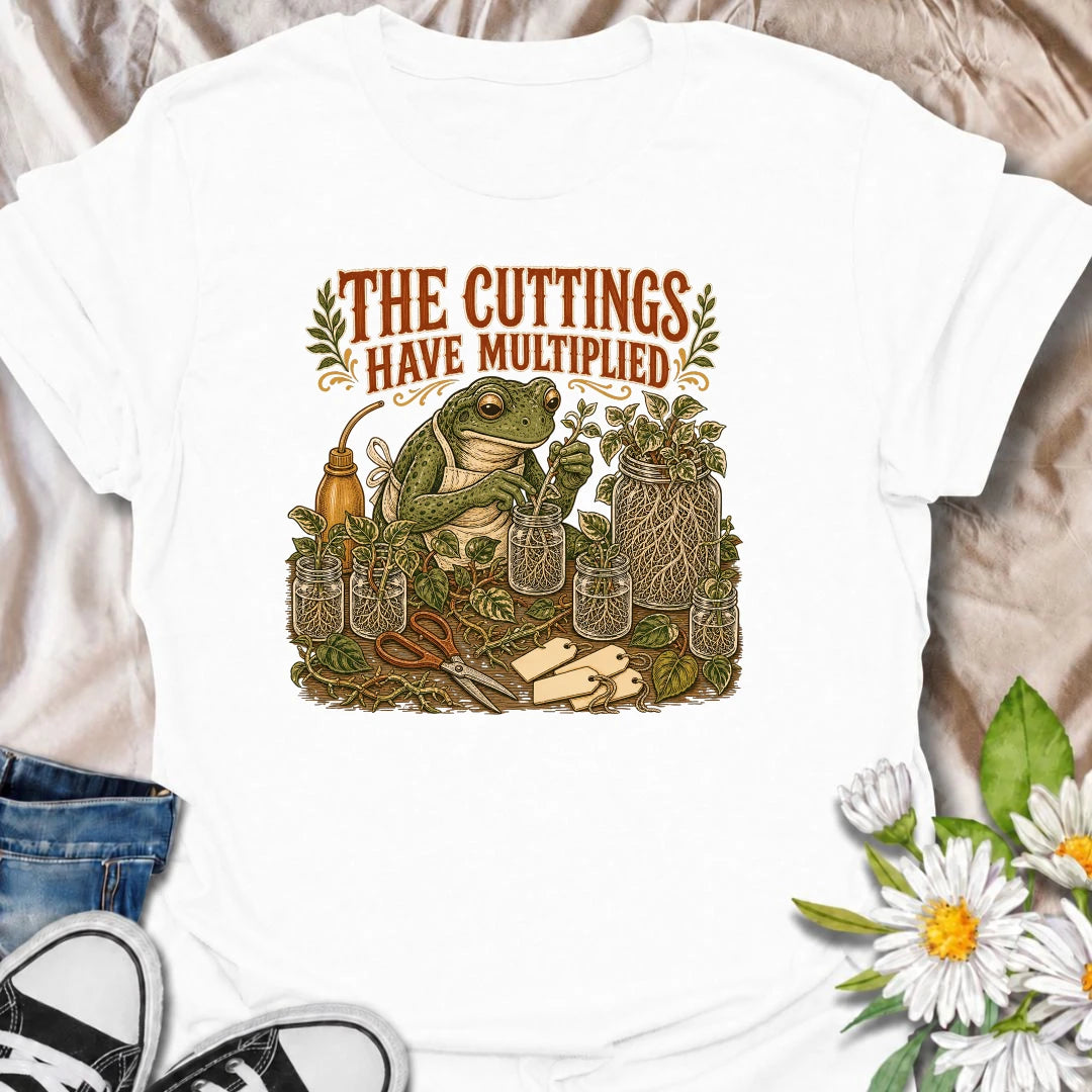 Celebrate a propagation collection that keeps growing with this funny “The Cuttings Have Multiplied” T-shirt. Featuring a charming frog surrounded by rooted plant cuttings, glass jars, scissors, and trailing vines, it is perfect for enthusiastic houseplant propagators. A playful gift for plant moms, pothos lovers, and anyone whose plant babies have taken over.