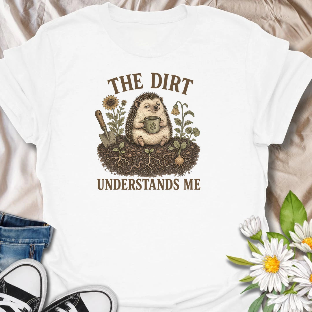 This The Dirt Understands Me t-shirt is perfect for gardeners who feel most at home with soil, seedlings, flowers, and a warm drink nearby. Featuring a cozy hedgehog sitting in the garden with a mug, trowel, roots, blooms, and earthy botanical details, this design is great for plant lovers, backyard gardeners, cottage garden fans, nature lovers, and anyone who feels understood by the dirt.