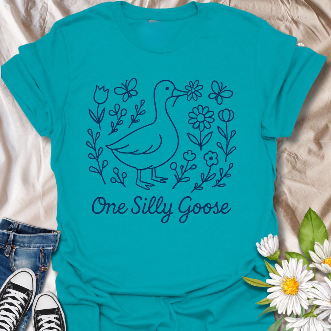 Adorable ‘One Silly Goose’ shirt with a playful goose surrounded by flowers and butterflies. Perfect for humor lovers, goose enthusiasts, and whimsical nature apparel fans.
