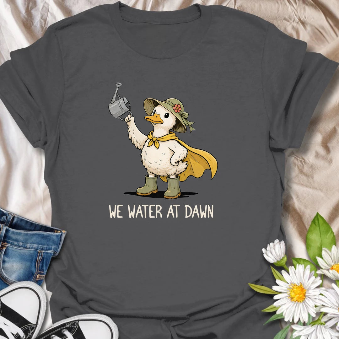 Water At Dawn t-shirt for gardeners who take their morning watering routine very seriously.
The cute duck gardener design adds playful garden charm with boots, a sunhat, cape, and watering can.
It is perfect for plant lovers, cottage garden fans, and anyone who starts the day checking on their flowers.
A sweet and funny gift for gardeners who believe the plants must be watered before anything else happens.