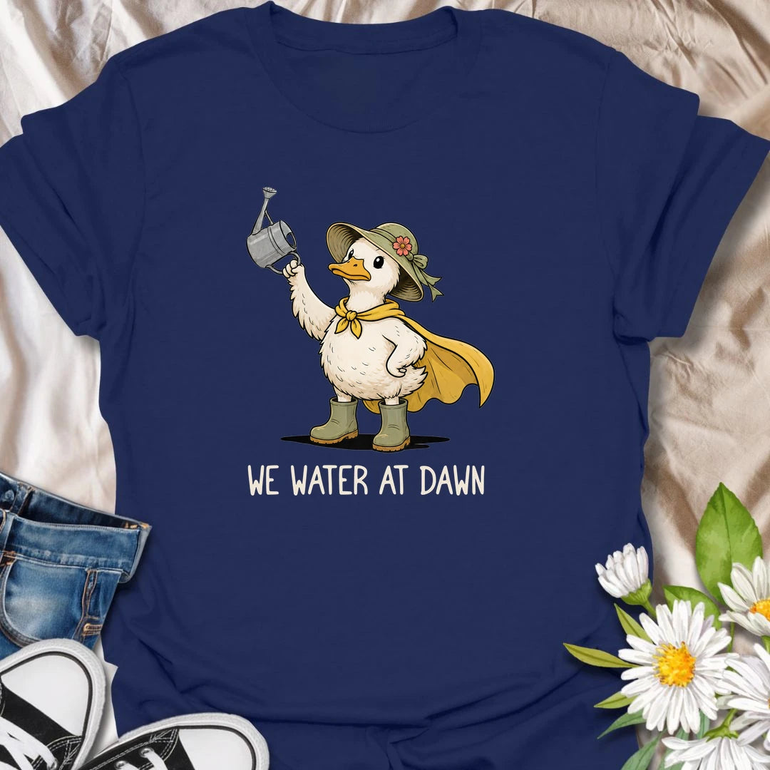 Water At Dawn t-shirt for gardeners who take their morning watering routine very seriously.
The cute duck gardener design adds playful garden charm with boots, a sunhat, cape, and watering can.
It is perfect for plant lovers, cottage garden fans, and anyone who starts the day checking on their flowers.
A sweet and funny gift for gardeners who believe the plants must be watered before anything else happens.