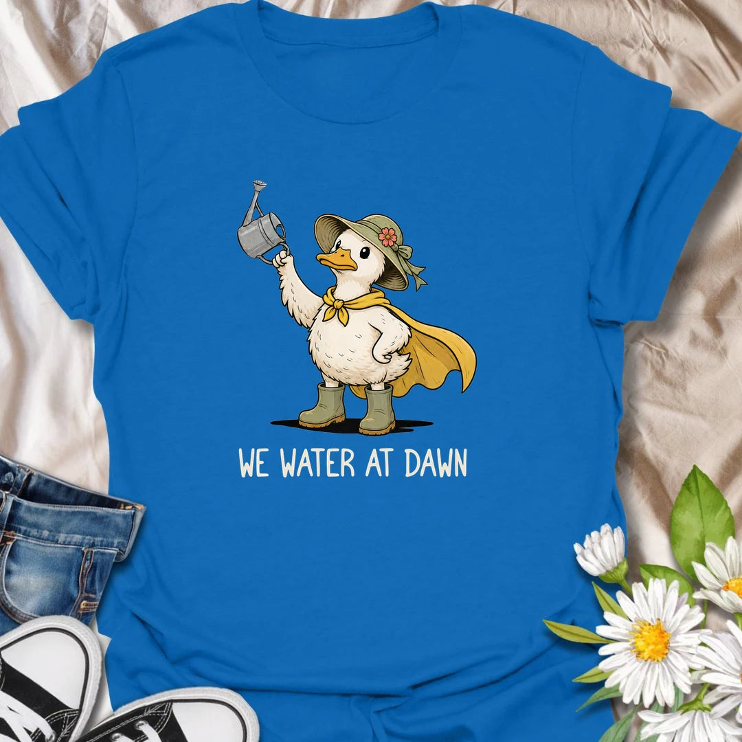 Water At Dawn t-shirt for gardeners who take their morning watering routine very seriously.
The cute duck gardener design adds playful garden charm with boots, a sunhat, cape, and watering can.
It is perfect for plant lovers, cottage garden fans, and anyone who starts the day checking on their flowers.
A sweet and funny gift for gardeners who believe the plants must be watered before anything else happens.