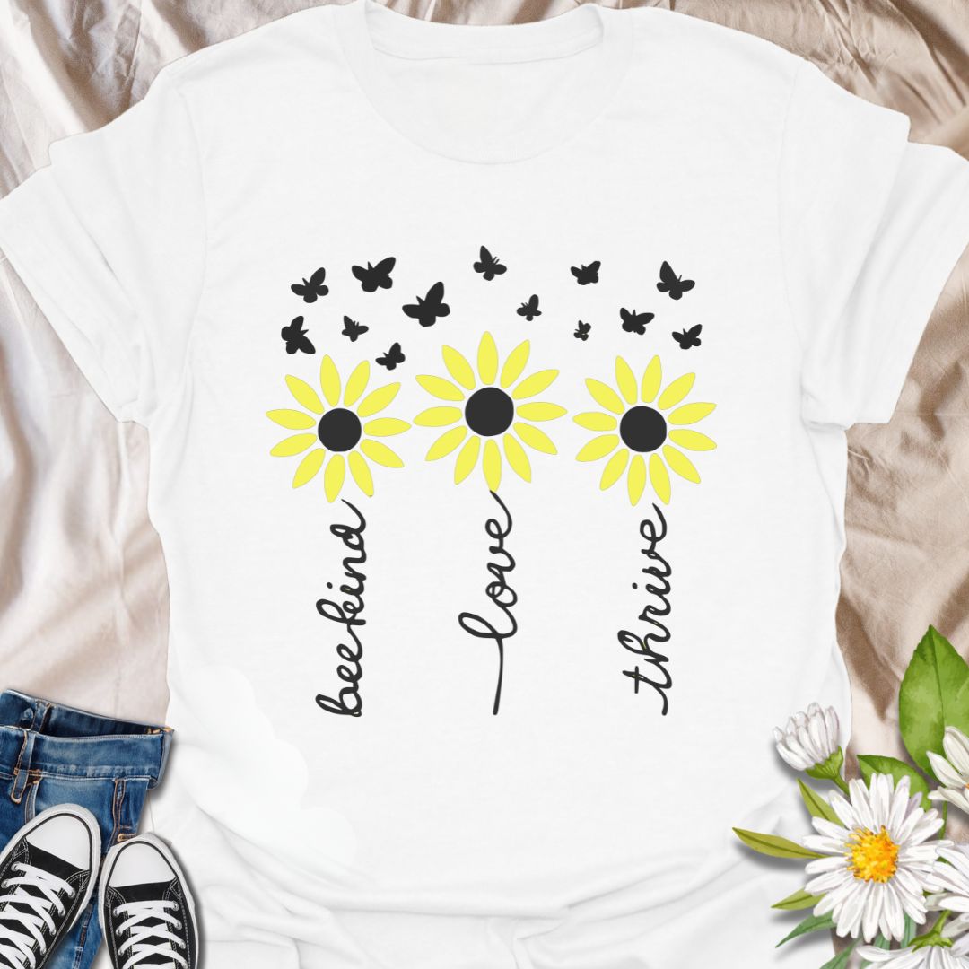 Inspire positivity with this uplifting floral graphic t-shirt featuring hand-lettered words be kind, love, thrive paired with charming daisies and fluttering butterflies. A perfect gift for flower lovers, kind souls, and anyone