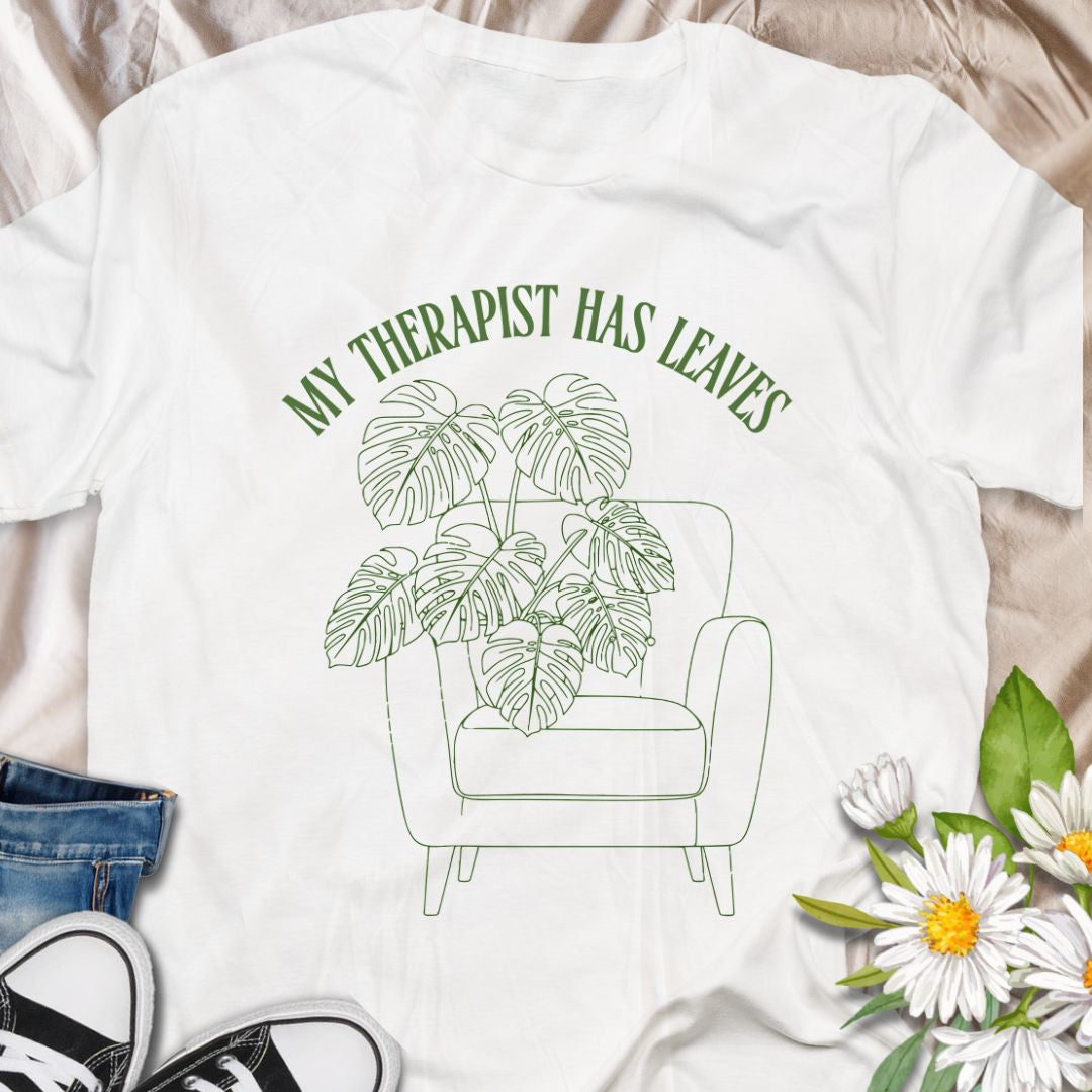For plant people who spill their heart out to their houseplants, this “My Therapist Has Leaves” t-shirt says it all. Features a cozy armchair and lush monstera, making it the perfect aesthetic plant lover tee for self-care days.