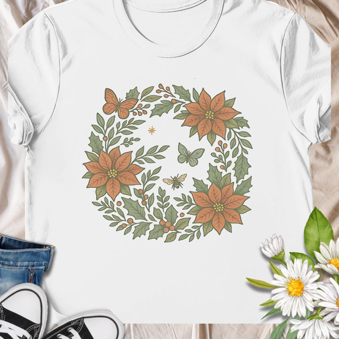 Festive botanical tee featuring a Christmas wreath with poinsettias, bees, and butterflies. Perfect holiday wear for plant lovers.