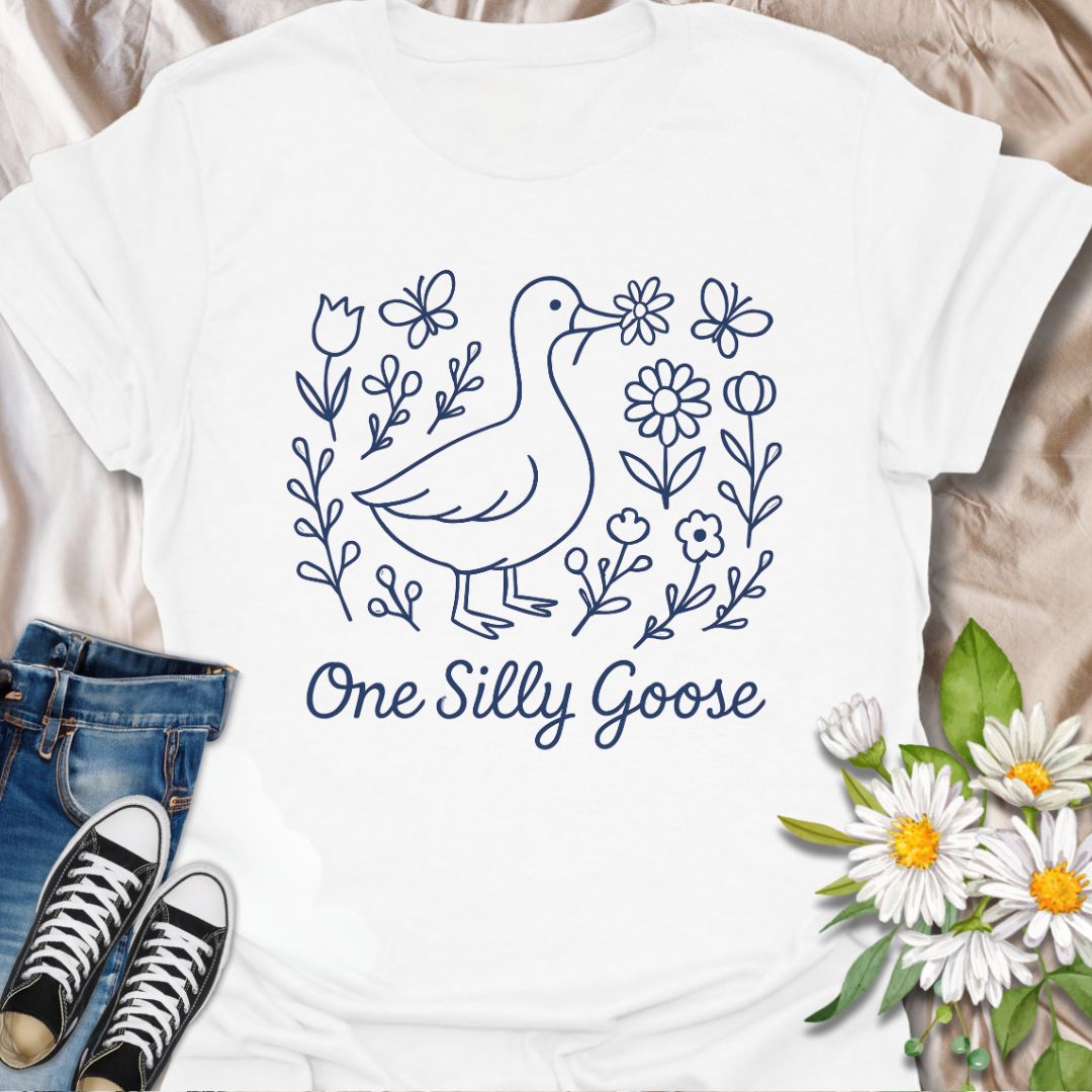 Adorable ‘One Silly Goose’ shirt with a playful goose surrounded by flowers and butterflies. Perfect for humor lovers, goose enthusiasts, and whimsical nature apparel fans.
