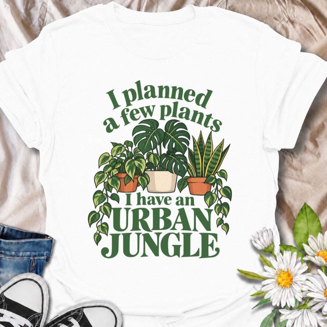A funny plant T-shirt for anyone who started with a few houseplants and somehow ended up living in an indoor jungle. The phrase “I Planned a Few Plants. I Have an Urban Jungle.” captures the familiar reality of plant collecting with light, relatable humor. Featuring monstera, pothos, and snake plants, this design is perfect for plant parents, houseplant collectors, and indoor gardeners. It makes a great gift for anyone whose shelves, windowsills, and corners have slowly disappeared behind greenery. Perfect 