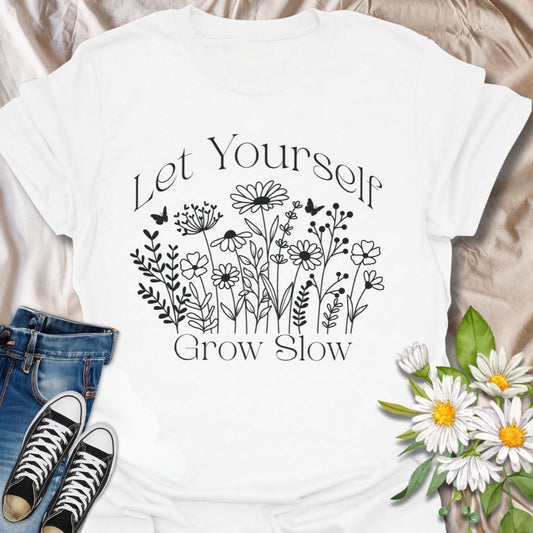 Embrace mindful living and personal growth with the "Let Yourself Grow Slow" t-shirt. Featuring a calming hand-drawn wildflower design with delicate butterflies, this motivational floral tee promotes self-love, mental wellness, and the beauty of growing at your own pace. Perfect for nature lovers, gardeners, and anyone on a self-care journey, this shirt brings comfort and encouragement in a stylish botanical aesthetic.