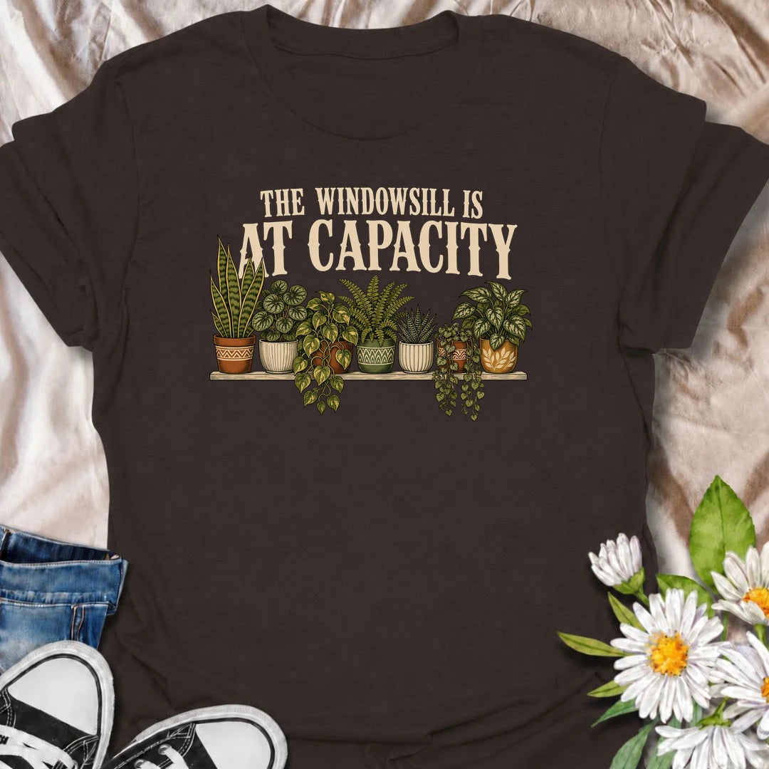 A funny houseplant T-shirt for anyone whose windowsill has officially run out of room. Featuring a packed row of potted houseplants, this design is perfect for plant parents, indoor gardeners, and collectors who keep finding space for just one more. The phrase “The Windowsill Is at Capacity” captures the reality of a growing indoor jungle with dry, relatable humor. It makes a great gift for pothos lovers, succulent fans, and anyone whose best window is permanently reserved for plants. Ideal for plant swaps,