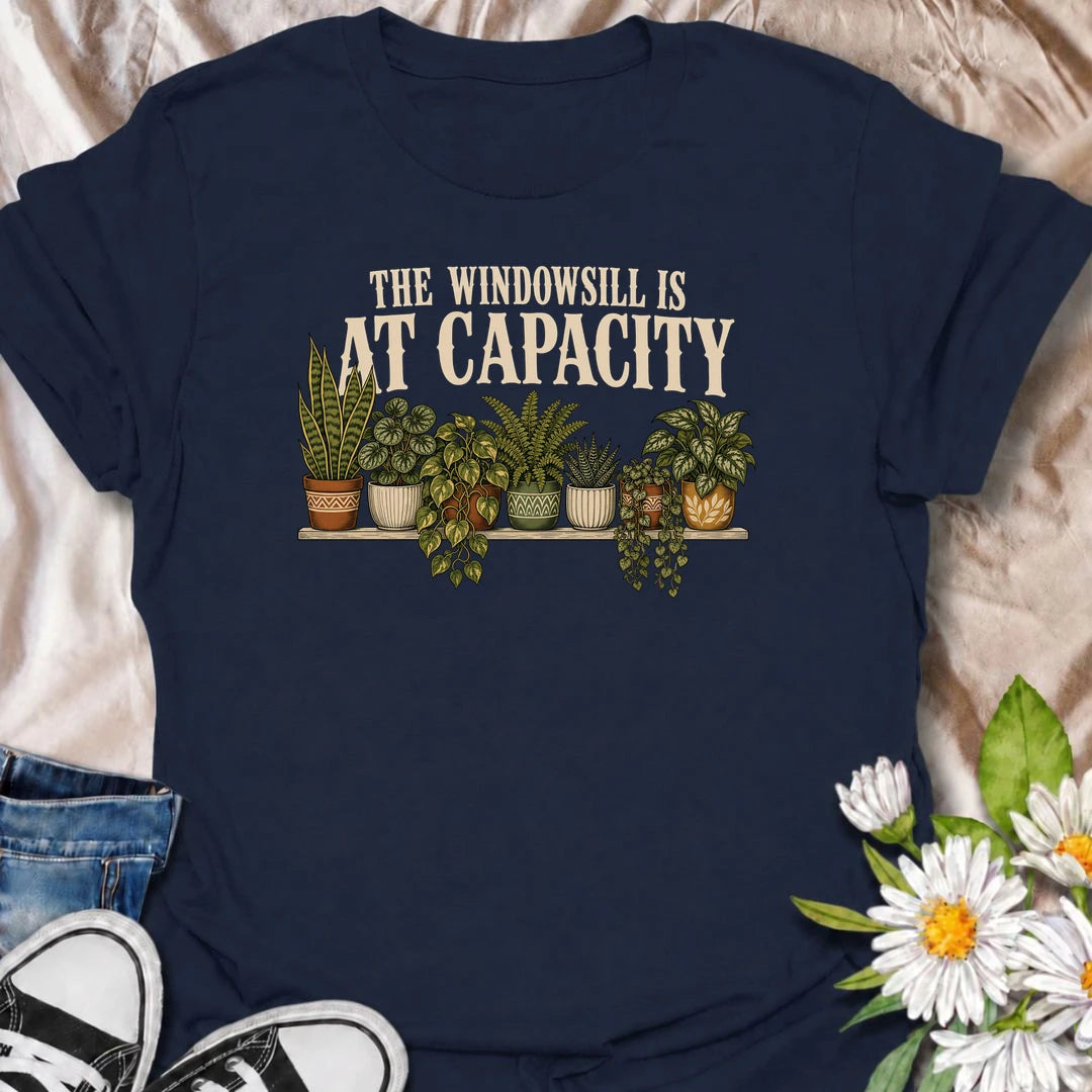 A funny houseplant T-shirt for anyone whose windowsill has officially run out of room. Featuring a packed row of potted houseplants, this design is perfect for plant parents, indoor gardeners, and collectors who keep finding space for just one more. The phrase “The Windowsill Is at Capacity” captures the reality of a growing indoor jungle with dry, relatable humor. It makes a great gift for pothos lovers, succulent fans, and anyone whose best window is permanently reserved for plants. Ideal for plant swaps,