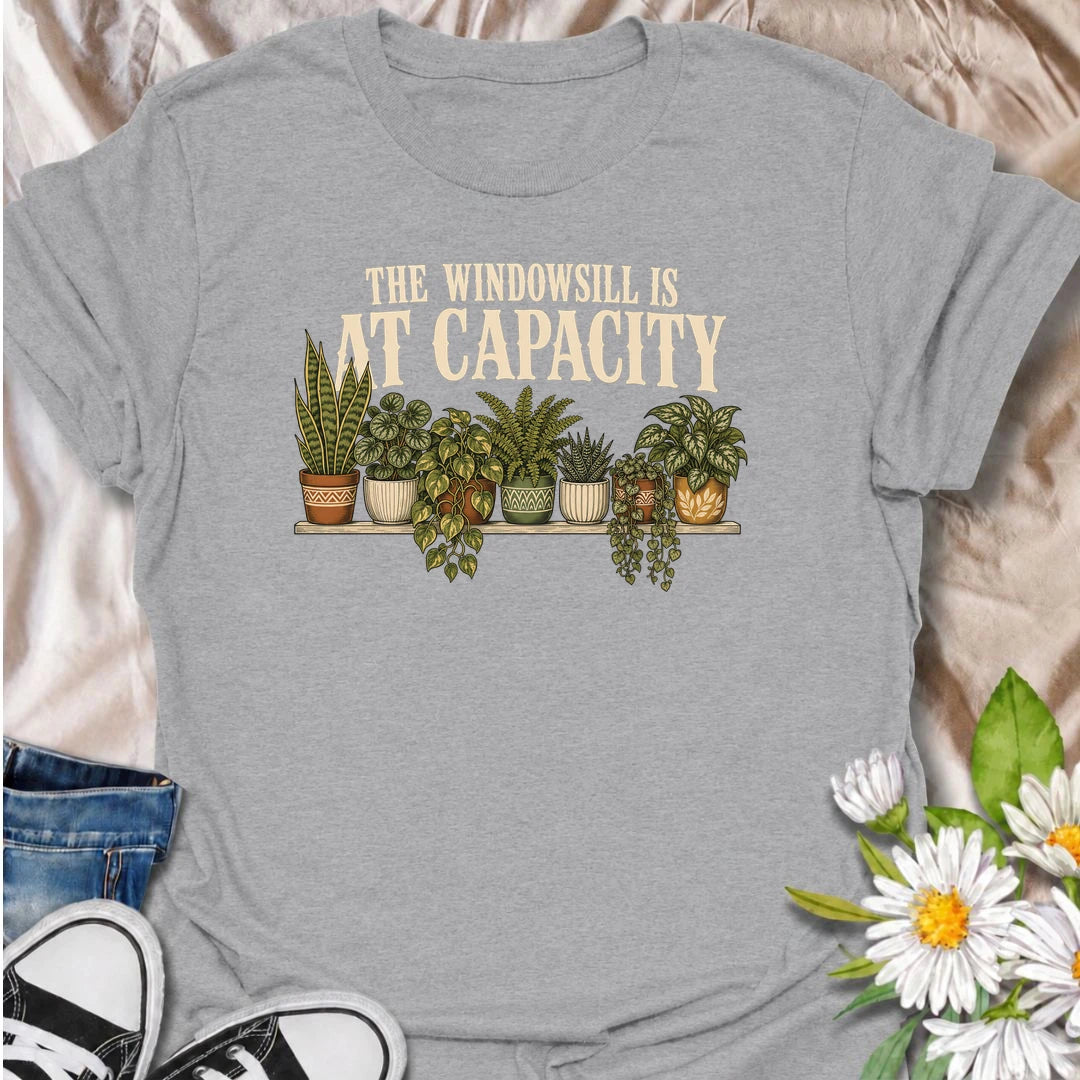 A funny houseplant T-shirt for anyone whose windowsill has officially run out of room. Featuring a packed row of potted houseplants, this design is perfect for plant parents, indoor gardeners, and collectors who keep finding space for just one more. The phrase “The Windowsill Is at Capacity” captures the reality of a growing indoor jungle with dry, relatable humor. It makes a great gift for pothos lovers, succulent fans, and anyone whose best window is permanently reserved for plants. Ideal for plant swaps,